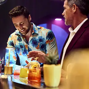 Two guys chatting in a bar onboard Virgin Voyages
