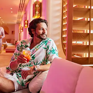 A bearded man staring out the window on a Virgin Voyages ship
