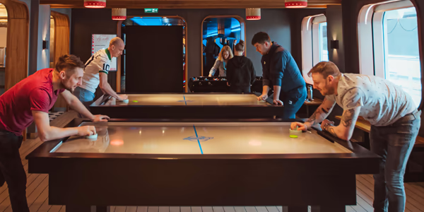 Two guys playing air hockey on Virgin Voyages
